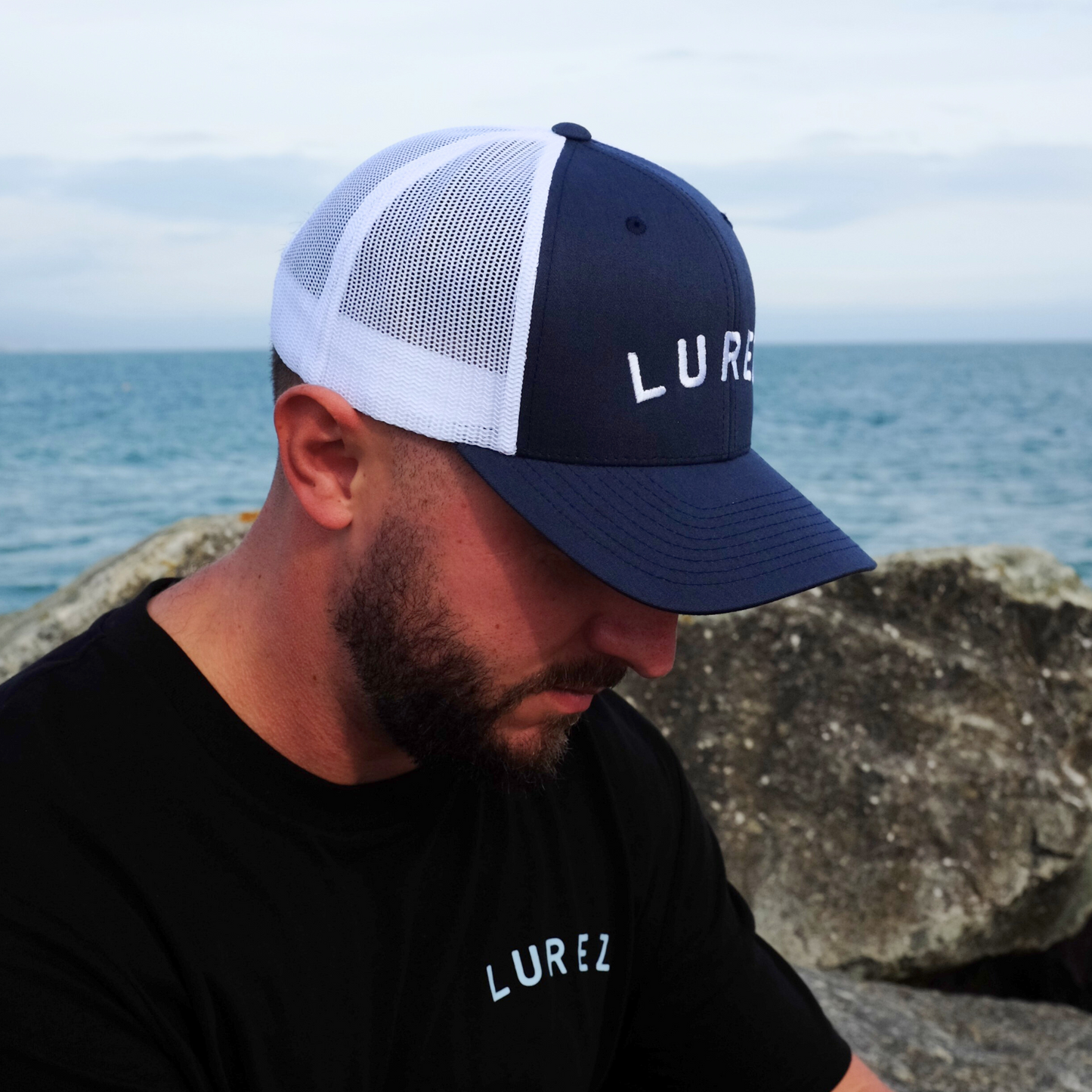 Man wearing navy lurez trucker on rocks