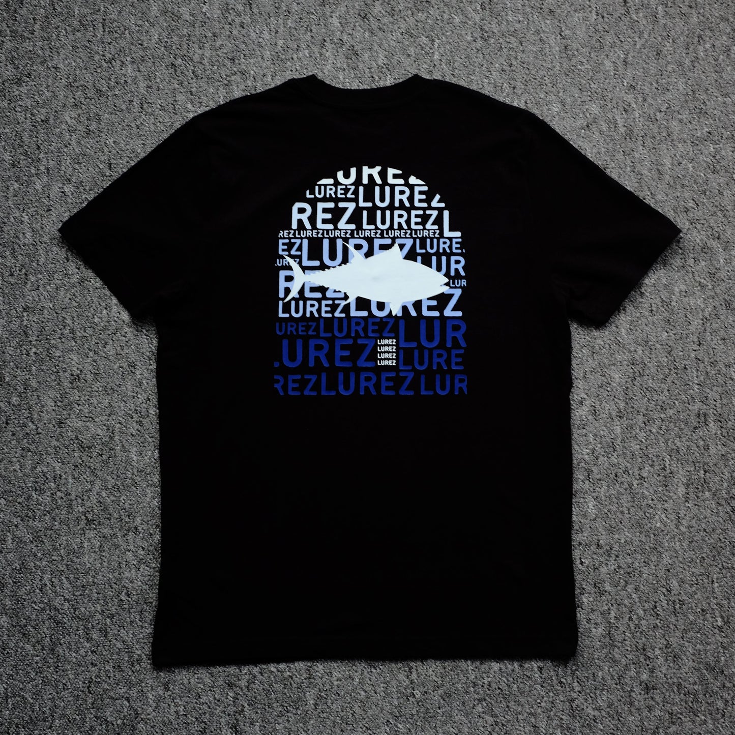 Black t-shirt with white and blue text on a gray surface