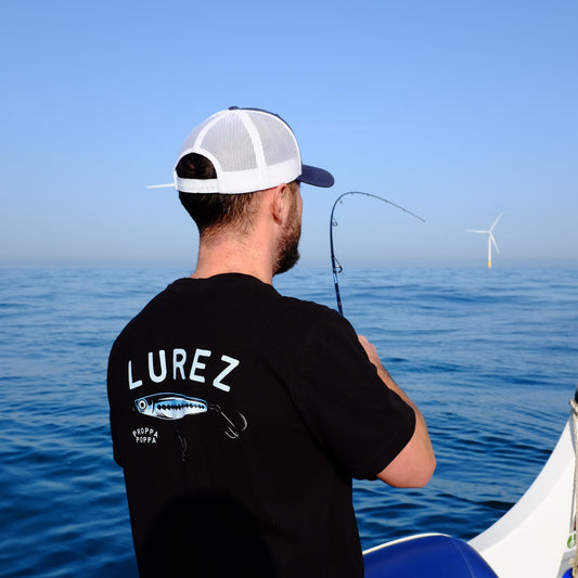 Person wearing a black hoodie with 'LUREZ' branding on a boat against a blue sky.