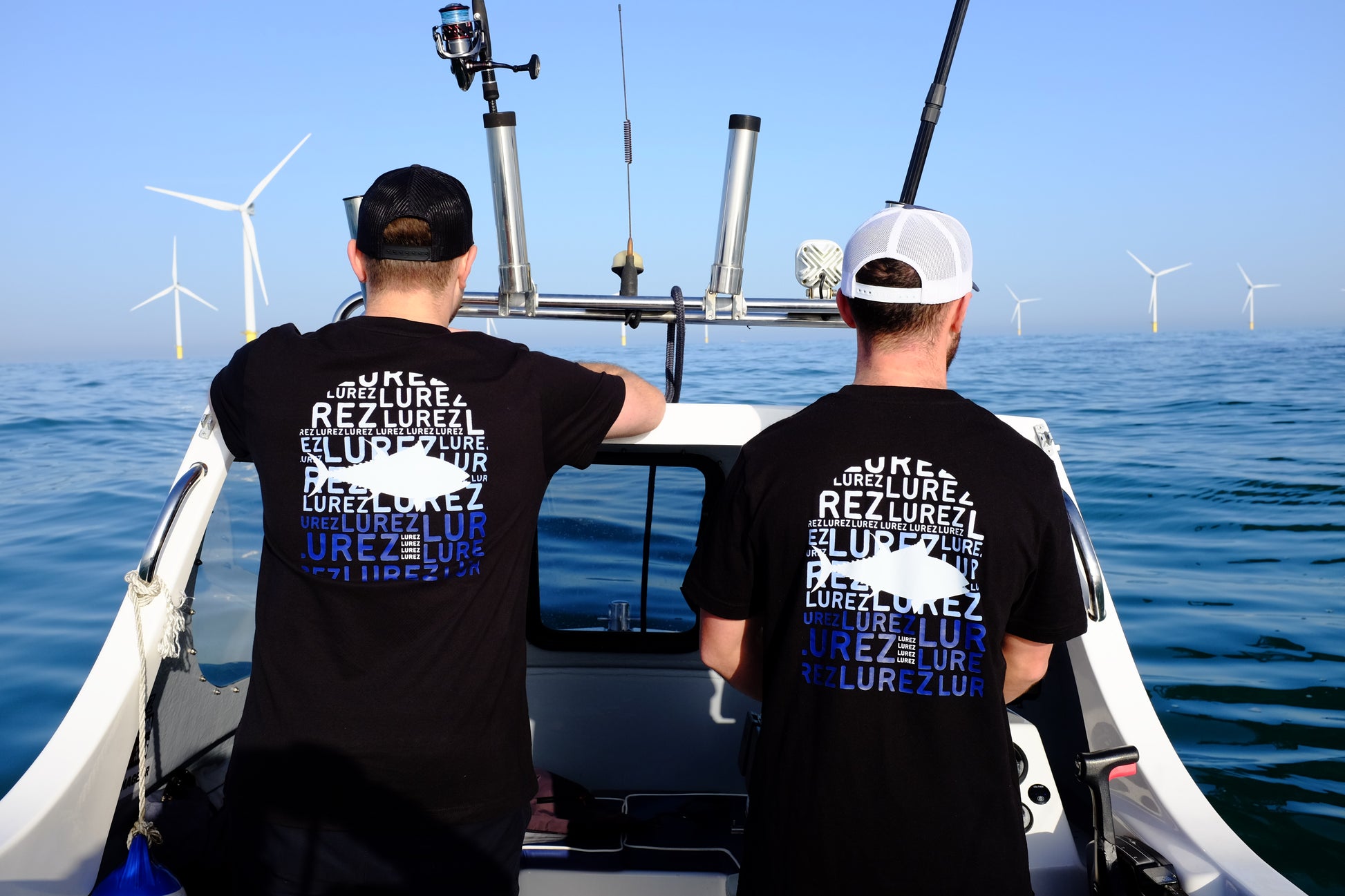 Two people on a boat with wind turbines in the background